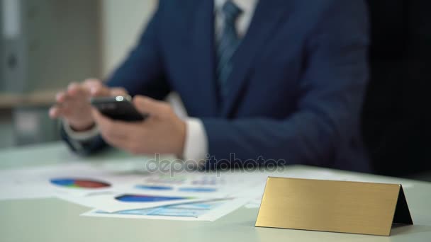 Hombre ocupado en traje usando teléfono, documentos en la mesa, plantilla de placa de nombre en blanco — Vídeos de Stock