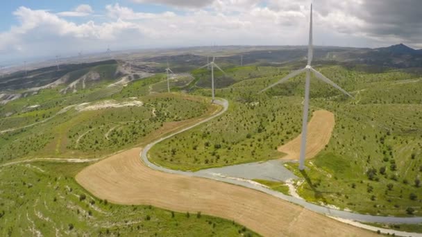 Paisagem incrível coberta com plantas verdes, enormes pás de turbina eólica girando — Vídeo de Stock