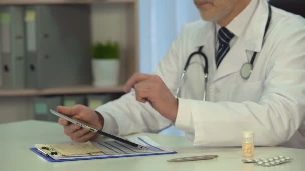 Médico varón consultando al paciente en línea, comprobando el diagnóstico en tableta en clínica — Vídeo de stock