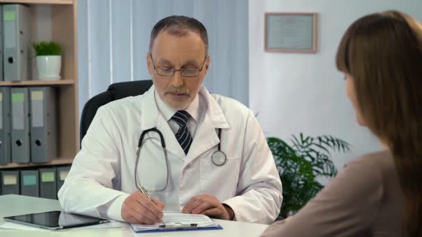 Frau spricht mit Arzt, Arzt verschreibt Patientin in Klinik Medikamente — Stockvideo