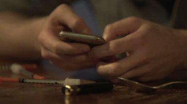 Erkek uyuşturucu bağımlısı smartphone, tablo üzerinde birçok şırınga mesaj yazarak heyecanlı