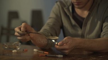 Erkek uyuşturucu bağımlısı eroin doz çakmak, kaşıkla hazırlanıyor masaya batar