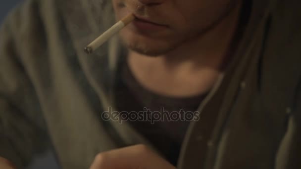 Hombre joven encendiendo cigarrillo, drogadicto y adicto al juego jugando en el teléfono inteligente — Vídeo de stock