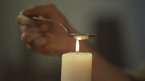 Hand of person heating chemical substance in spoon on candle light, drug abuse — Stock Video