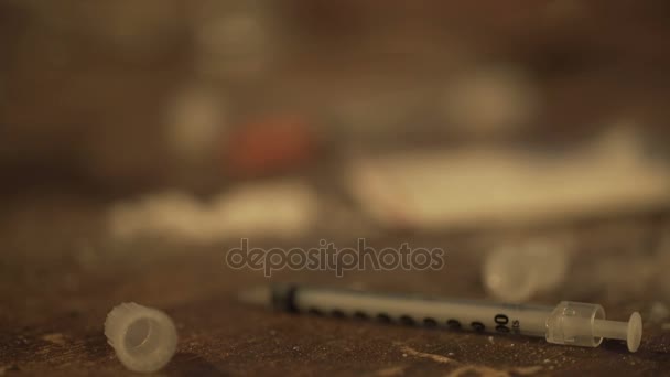 Arm of person abusing drugs lying on table among used syringes and cigarettes — Stock Video