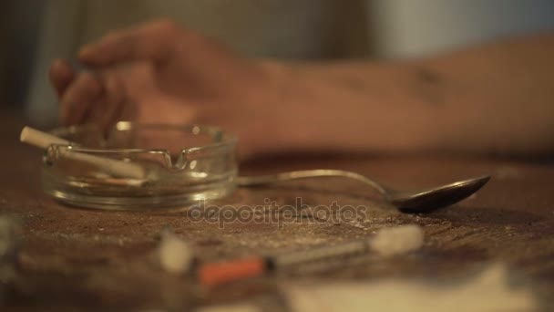 Ręką człowieka cierpieniem uzależnienia od narkotyków, leżącego na stole shabby, tanie motel Room — Wideo stockowe