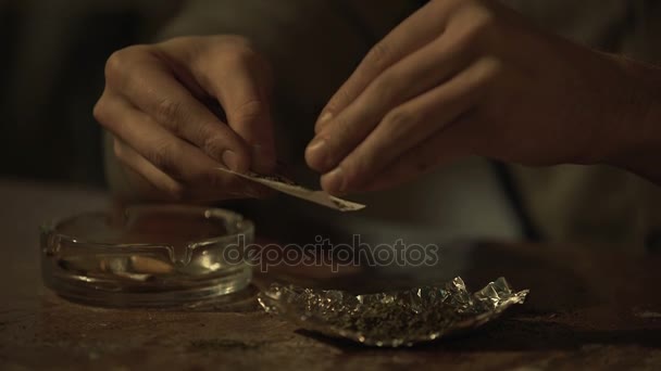 Manos de hombre joven rodando cigarrillo de marihuana medicinal para aliviar el dolor crónico — Vídeo de stock