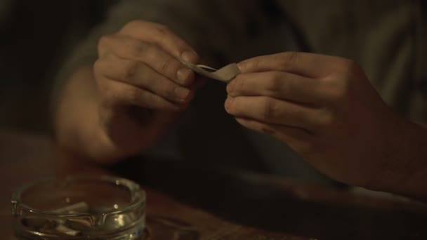 Joven deprimido preparando cigarrillo de cannabis para la euforia y la alucinación — Vídeos de Stock