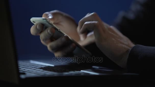 Homem trabalhando horas extras no escritório até tarde, enviando mensagem para a esposa no smartphone — Vídeo de Stock