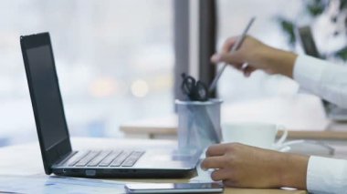 Eller kalemle notlar yazma ve tipik haber dizüstü bilgisayarda kadın Sekreter