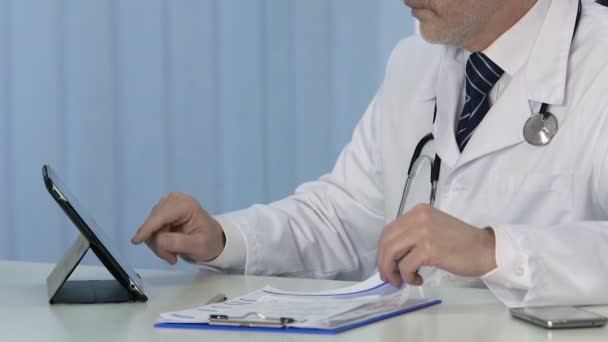 Clinic doctor inserting data in electronic medical records on modern tablet pc — Stock Video