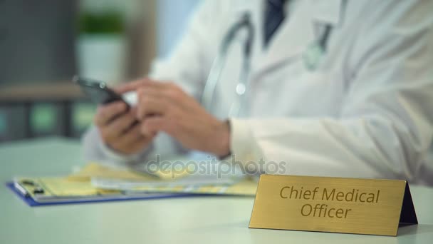 Manos del jefe médico páginas de desplazamiento oficial en el teléfono inteligente en la clínica — Vídeo de stock