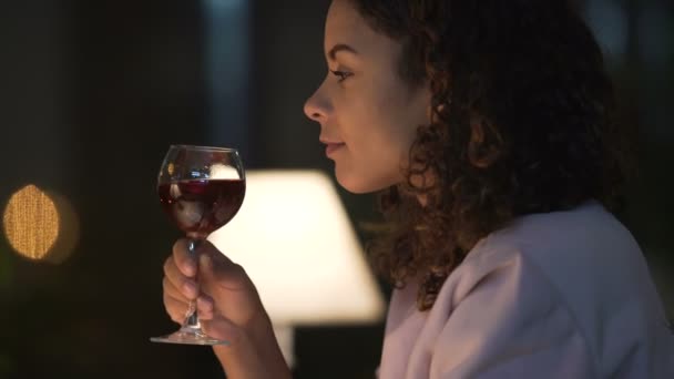 Biracial dama bebiendo vino y leyendo su libro favorito en acogedor restaurante — Vídeo de stock