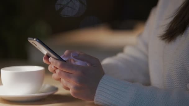 Jovem mulher entediada deslizando páginas no smartphone e beber chá no café — Vídeo de Stock