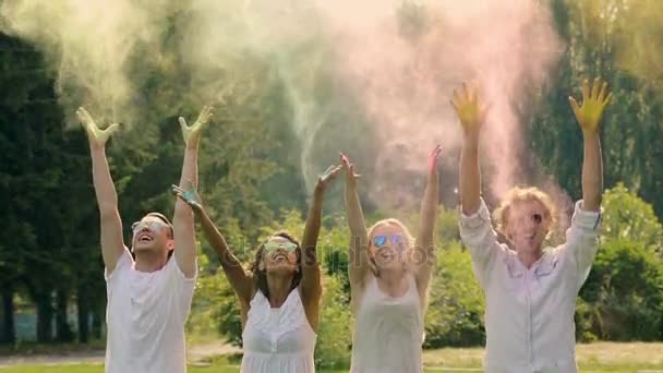 Cuatro jóvenes rociando el colorido polvo en cámara lenta extra, Holi fest — Vídeo de stock