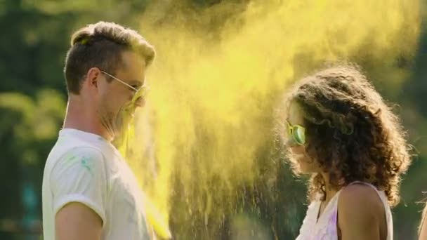 Dos parejas felices tirándose pintura en polvo, coqueteando y riendo — Vídeos de Stock