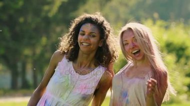 İki güzel kız gülümseyerek, cam renk Festivali için poz boya kaplı