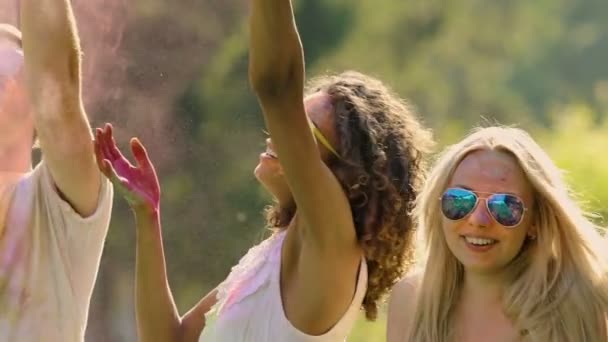 Lycklig bästa vänner dansa och hoppa i färgglada dammoln på Holi festival — Stockvideo