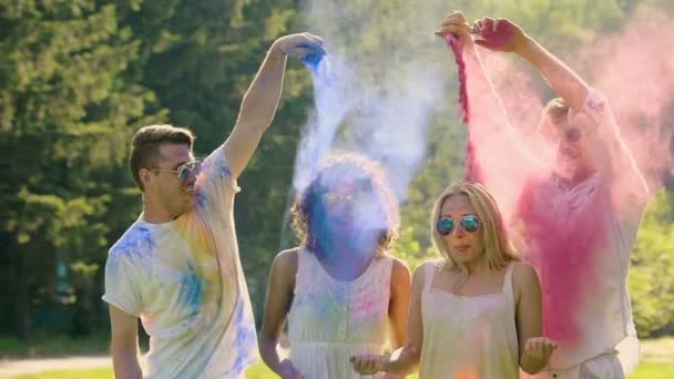 Coppia di ragazzi spruzzando polvere colorata in aria e alle loro ragazze — Video Stock