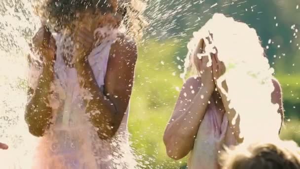 Dos mujeres jóvenes riendo se salpican con agua en el festival Color, cámara lenta — Vídeo de stock