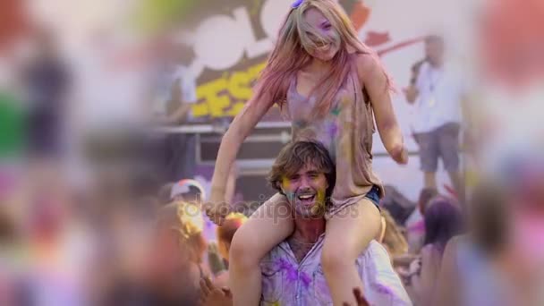 Geleneksel renk fest, erkek arkadaşının omuzlarında oturan güzel sarışın kız — Stok video
