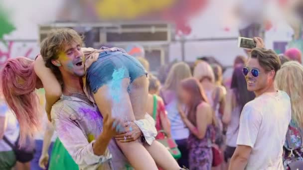 Excited boyfriend spanking girlfriend at Color festival, young people having fun — Stock Video