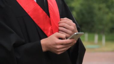 Erkek mezunu smartphone cep telefonu ile video selamlar izlerken sosyal ağlar kontrol