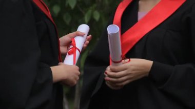 Kadın Mezunları Diploma tutarak ve geleceği hakkında konuşmak akademik elbiseler