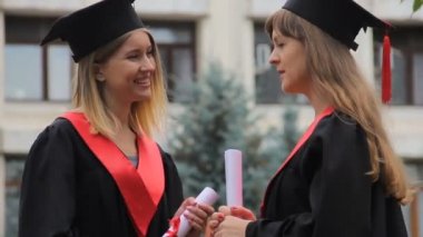 Mezunları Diploma tutarak ve mezun olduktan sonra konuşan akademik elbiseler