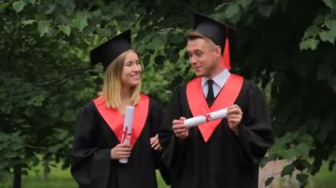 Parkta yürüyüş, diploma holding ve konuşmak mezunları birkaç gülümseyen