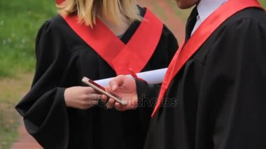 Erkek ve kadın yüksek lisans öğrencileri görüş Smartphone'da, mezuniyet fotoğraf