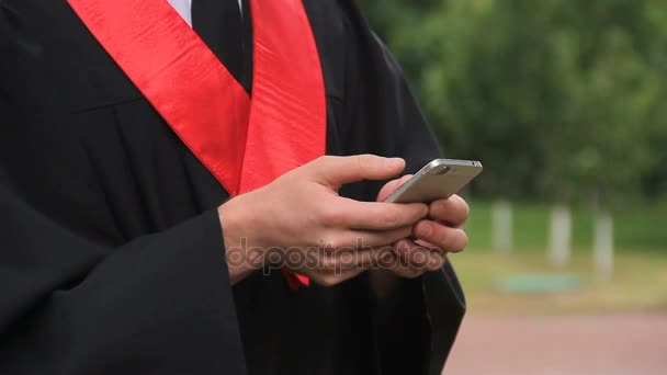 Universitätsabsolvent blättert Nachrichten auf dem Smartphone, Mann im Kleid schiebt Seiten — Stockvideo