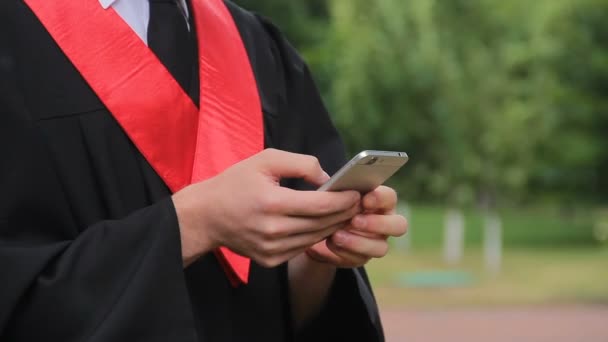 Hombre graduado charlando y comprobando el correo electrónico en el teléfono inteligente, las tecnologías modernas — Vídeo de stock