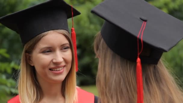 Friends graduates talking in park near university after graduation ceremony — Stock Video