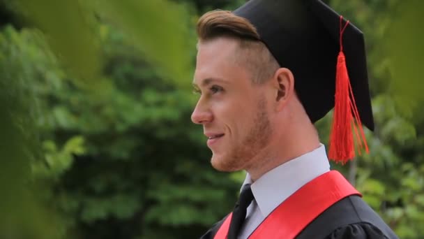 Joven estudiante graduado feliz sonriendo y posando para la cámara, sesión de fotos — Vídeo de stock