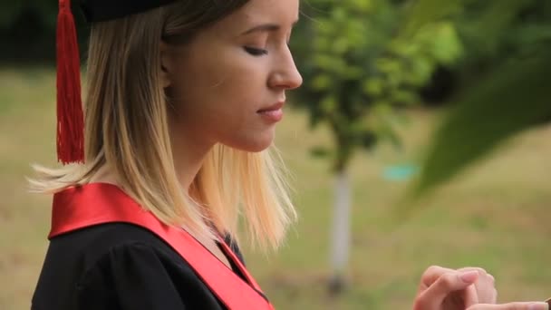 Bastante mujer graduada en gorra académica charlando con su novio en smartphone — Vídeos de Stock