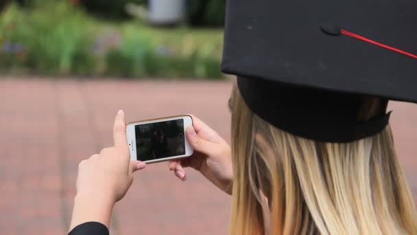 Mujer graduada filmando a sus amigas en el celular y mostrando pulgares hacia arriba — Vídeos de Stock