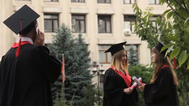 卒業式の日にスマート フォン上の挨拶を聞いて笑顔の学生 — ストック動画