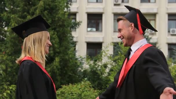 Mujer rubia en vestido de graduación abrazando mejor amigo después de recibir el diploma — Vídeos de Stock