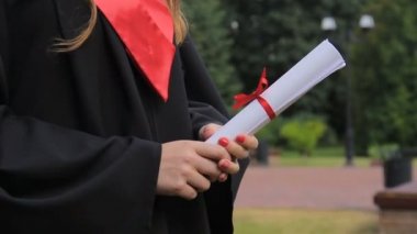 Holding diploma, mezuniyet töreni zevk akademik elbiseli genç kadın