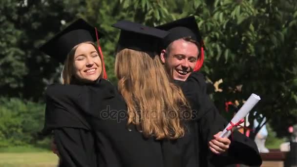 Estudiantes alegres felicitándose y abrazándose en la ceremonia de graduación — Vídeos de Stock