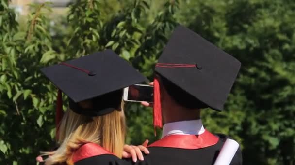 Couple of joyful graduates recording video on smartphone, graduation ceremony — Stock Video