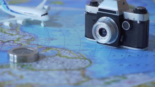 Подорожі аксесуари та іграшковий літак на фоні карти світу, планування відпусток — стокове відео