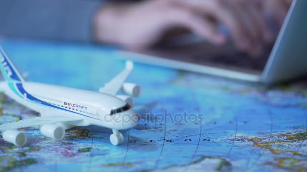 Flygplan modell närbild, oskärpa person bokar flygbiljetter online på laptop — Stockvideo