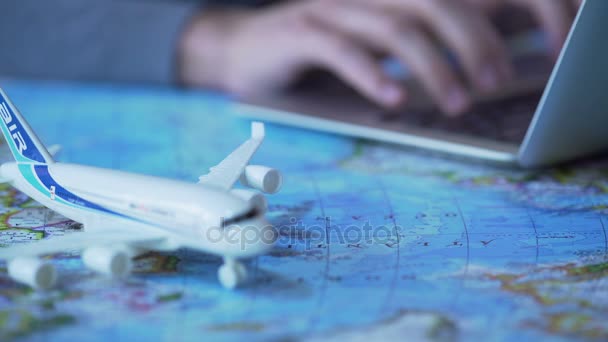 Prenotazione volo uomo per viaggio d'affari, digitando sul computer portatile, modello aereo sulla mappa — Video Stock