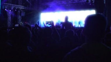 Müzik yıldız performans izliyor ve el sallayarak birçok insan siluetleri