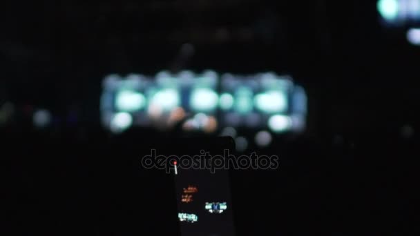 Persona filmando espectáculo de música en gadget, siluetas del público en la sala de conciertos — Vídeo de stock