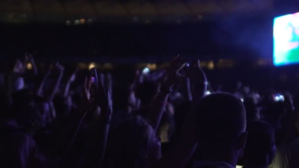 Натовп щасливих людей співає і танцює на концерті, знімаючи відео на гаджетах — стокове відео