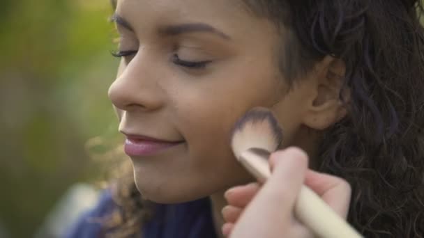 Artista de maquillaje profesional iguala el tono de la piel modelo con cepillo, rodaje de películas — Vídeos de Stock