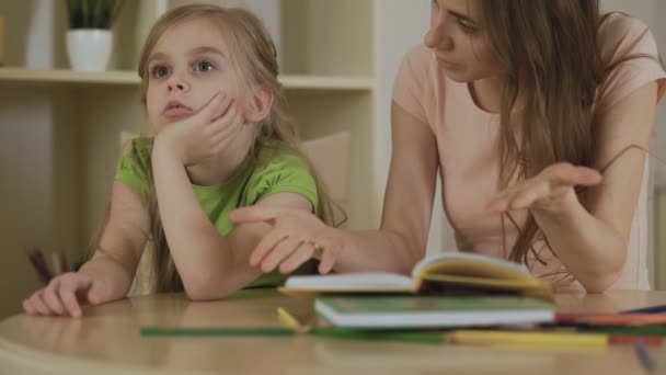 Annoyed woman hopelessly teaching little girl, naughty daughter ignoring mother — Stock Video